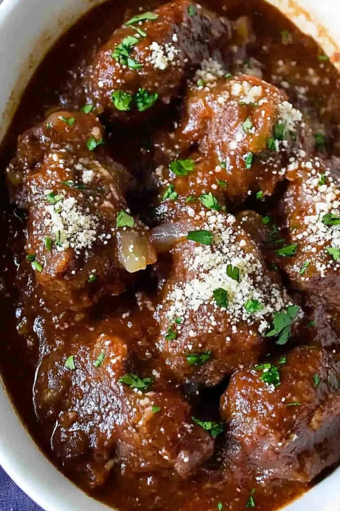 Zarte Fleischbällchen in einer reichhaltigen Tomatensauce, garniert mit frischem Koriander und geriebenem Parmesan.