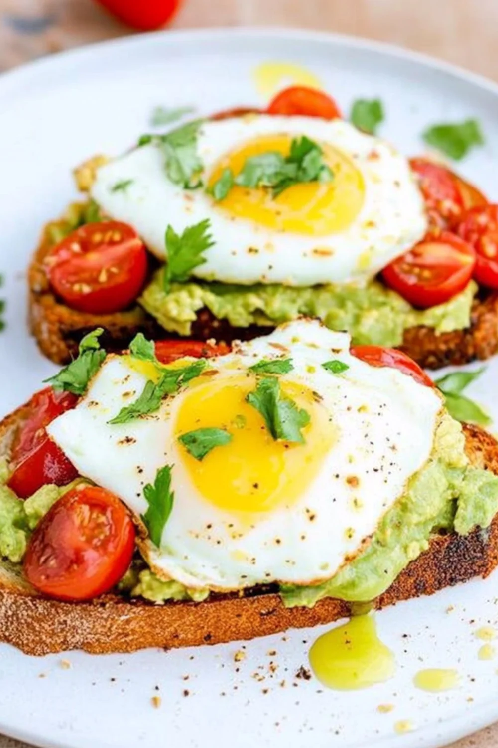 Avocado-Toast mit Tomaten, gebratenem Ei und frischem Koriander.