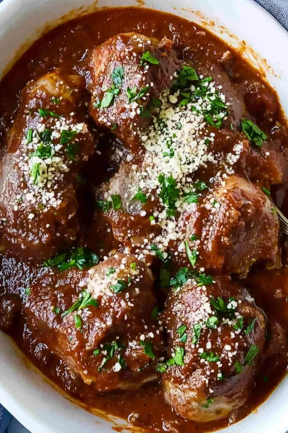 Zarte Fleischbällchen in einer reichhaltigen Tomatensauce, garniert mit frischem Koriander und geriebenem Parmesan.